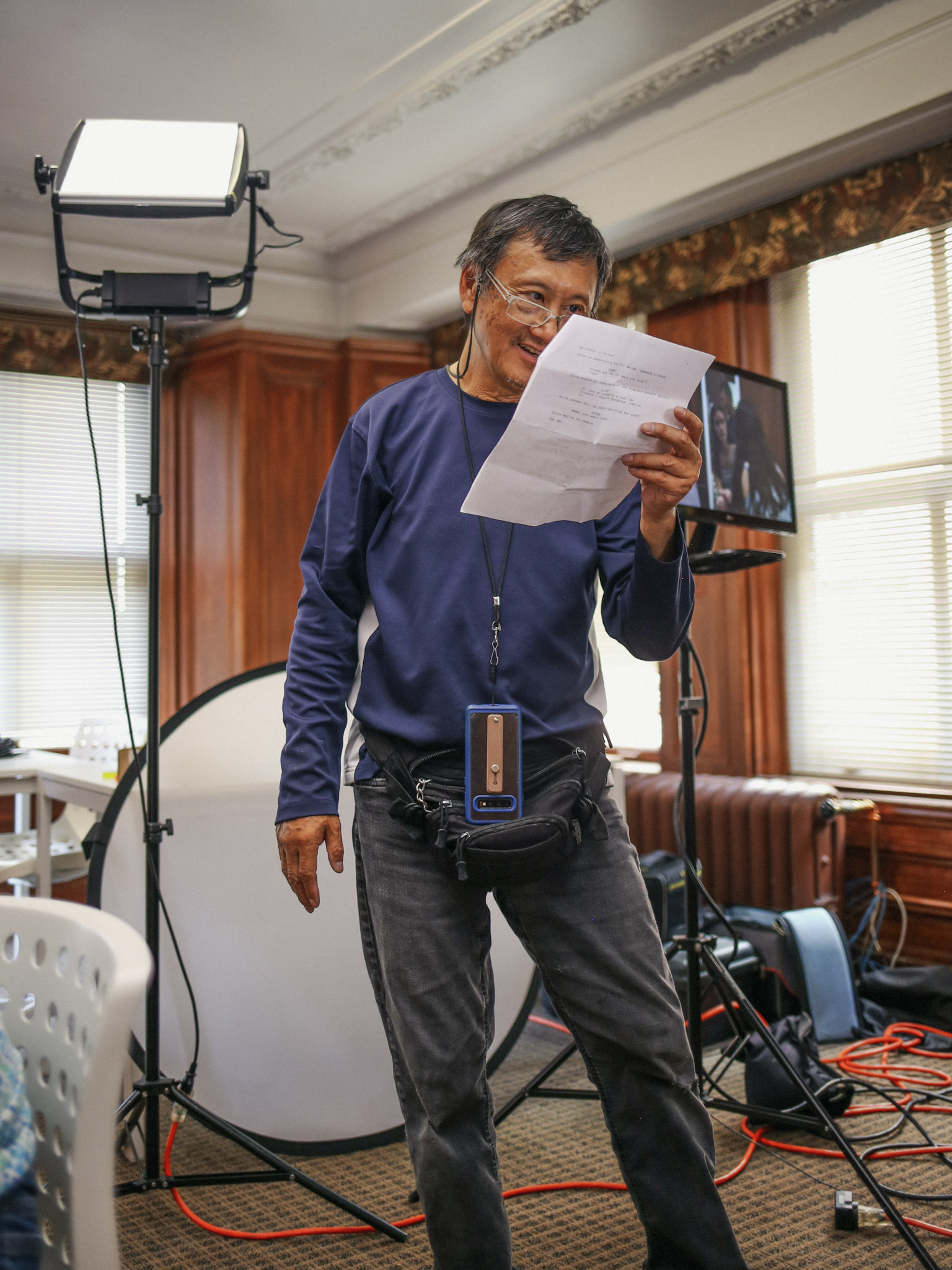 Instructor reading through a script on set beside a lighting stand and monitor