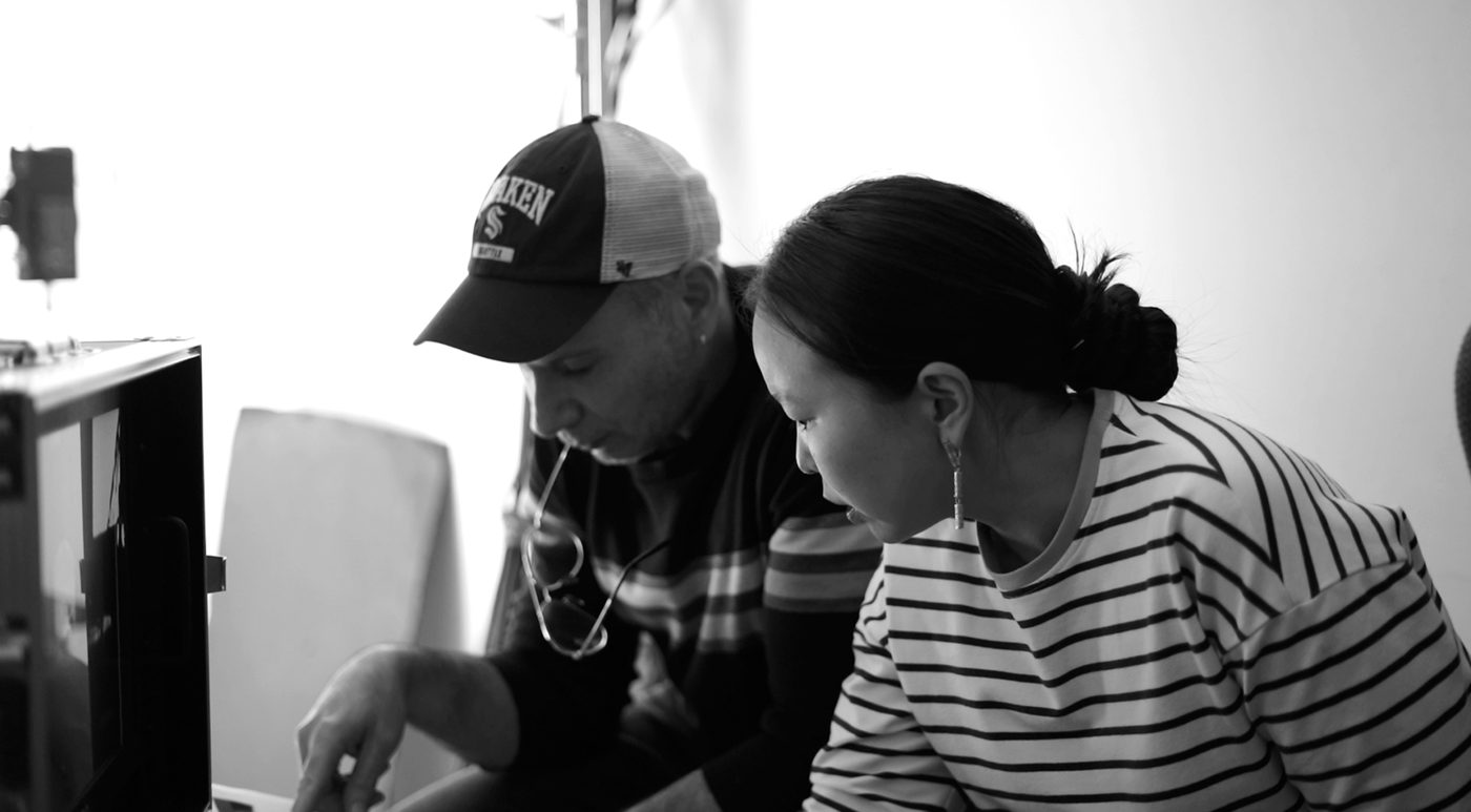 Black-and-white photo of a student and a mentor reviewing a take together on set